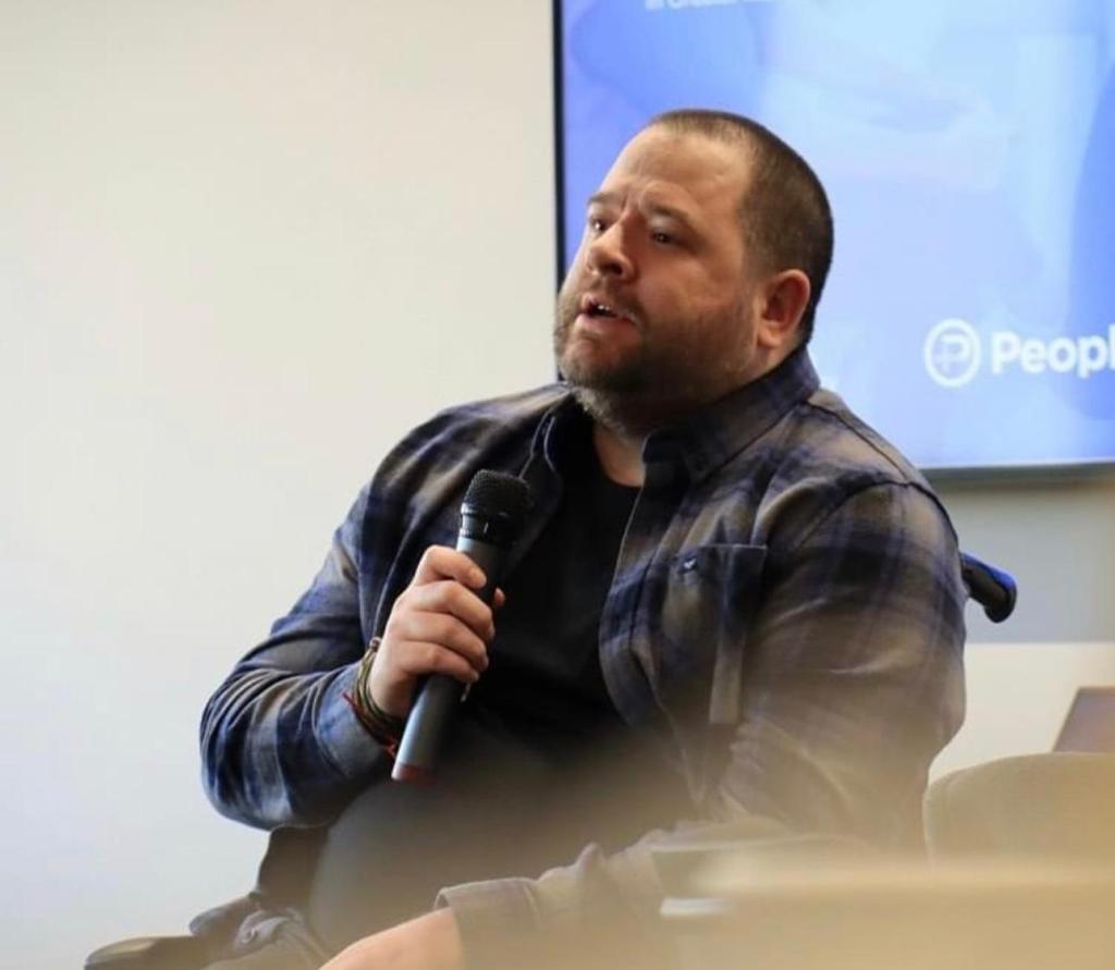 Scott Whitney holding a microphone at UA92 in Old Trafford Manchester as his spreads the word about disability inclusion